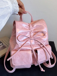 Pink glossy leather backpack with bow detail and drawstring closure for women