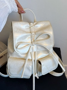 Chic cream bow backpack with glossy crinkled texture and front pockets for daily style