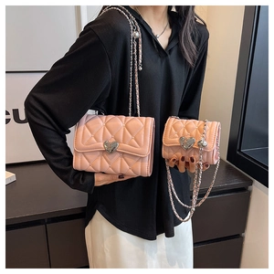 Détail de deux sacs à bandoulière matelassés roses avec boucles en métal argenté en forme de cœur