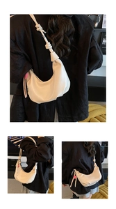 Detail of off-white hobo bag with knotted shoulder strap and pink heart charm