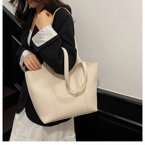 Detail of a large cream leather tote bag with lychee grain and dual handles