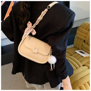 Borsa a tracolla beige con sciarpa di seta sulla tracolla e ciondolo di peluche indossata