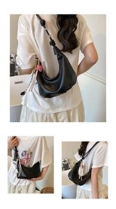Detail of black crescent hobo bag with knotted strap, pink heart charm and ribbon