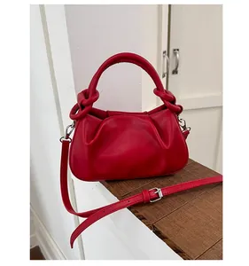 Detail of red leather bag with unique knotted handle and adjustable shoulder strap