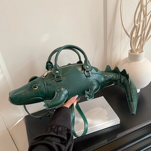 Dettaglio laterale di borsa a mano a forma di coccodrillo verde scuro con tracolla