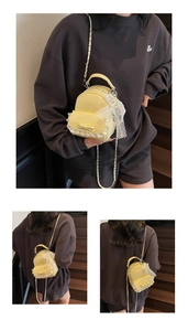 Detail of yellow mini backpack featuring white lace trim and metal chain strap