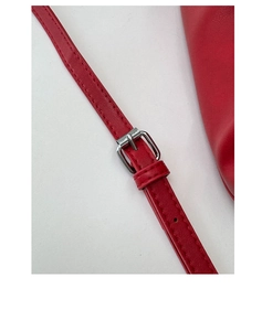Detail of red leather shoulder strap with adjustable silver buckle and neat stitching