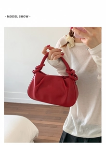 Red crossbody bag featuring a half-moon design and chunky knotted faux leather handle