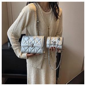 Détail d'un sac argenté matelassé à chaîne avec une boucle métallique en forme de cœur