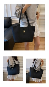 Detail view of large black leather tote bag with elegant golden twist lock and twin handles