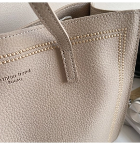 Macro shot of lychee-patterned leather tote bag featuring gold star stitching and logo