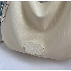 Détail du sac en similicuir beige montrant la texture fine et l'étiquette mode