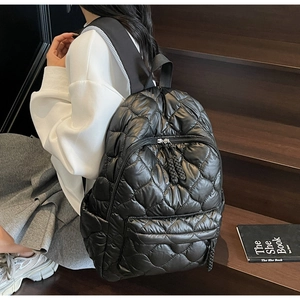 Macro shot of black quilted puffer backpack showing detailed stitching and nylon texture