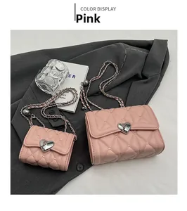 Détail de mini sacs matelassés roses avec fermoirs cœur argentés sur tissu gris chiné