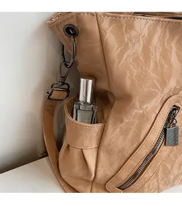 Detail view of light brown retro faux leather tote with side pocket and perfume bottle