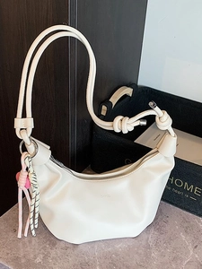 Chic beige crescent dumpling shoulder bag with knotted strap and tassel detail