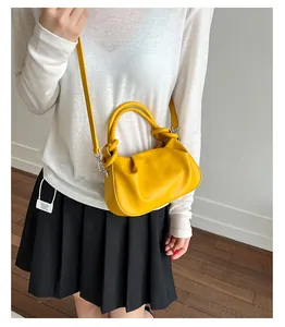 Detail of yellow crescent shoulder bag featuring cloud-style pleats and dual ring handles