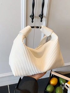 Sac hobo plissé blanc cassé élégant avec boucle argentée tenu dans un décor quotidien