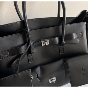 Detail view of silver metal buckles and stitching on the black leather tote bag