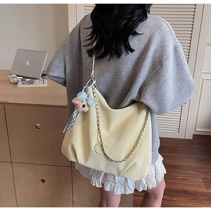 Détail du sac hobo jaune pâle avec chaîne argentée et mignon ours en peluche attaché