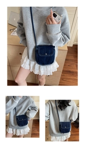 Detail showing a dark blue denim crossbody bag with flap cover and metal buckle closure