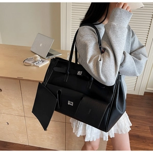 Close-up of black leather tote bag with metallic lock detail and minimalist design
