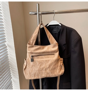 Detail of light beige tote bag featuring textured leather and front zipper pocket detail