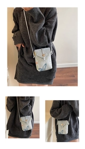 Detail of light blue mini crossbody phone bag featuring blue butterfly embroidery and gold heart lock