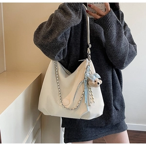 Détail du sac bandoulière blanc demi-lune avec chaîne en cuir et breloque ours