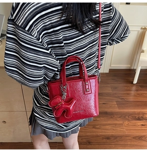 Detail of red patent leather bucket bag with a cute balloon dog charm and top handles