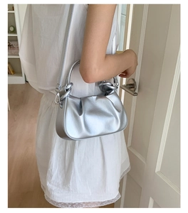 Close-up of metallic silver pleated handbag with circular handle and slender strap