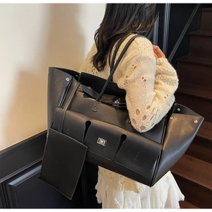 Close-up of black tote bag featuring multiple pockets, metal locks and extra small pouch