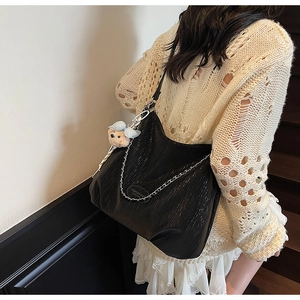 Détail du sac hobo en cuir noir avec chaîne argentée et charm ours en peluche