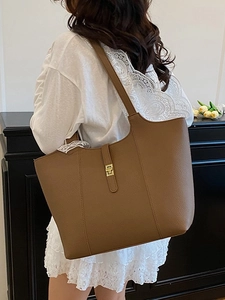 Brown lychee textured tote bag with gold metal buckle shown in a lifestyle setting