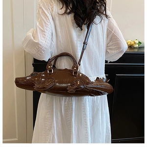 Borsa a mano marrone a forma di coccodrillo con texture in pelle su un vestito bianco