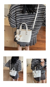 Detailed view of white PU leather bucket bag with puppy charm and chain strap