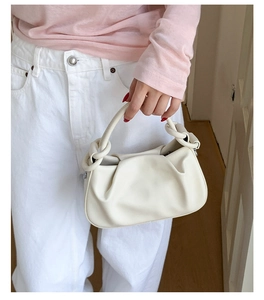 Detail of white pleated handbag showing soft leather texture and stylish circular handle rings