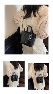 Detail of black glossy mini bucket bag with fashion lettering and dog charm