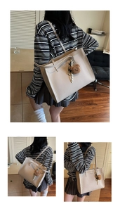 Detail of cream tote bag with lychee texture, stitching, and plush bear charm accent