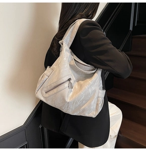 Detail of silver tote bag with metallic texture, side pockets, and crossbody strap