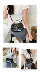 Detail of black quilted crossbody bag with metal chain handle and turn-lock closure
