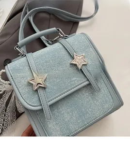 Detail of light blue denim handbag featuring white polka dots and silver star buckles