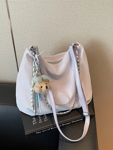 Sac à main violet en cuir souple avec bandoulière chaîne et pendentif ours sur un livre