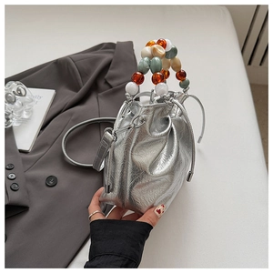 Detail of silver metallic bucket bag with colorful beaded handle and drawstring closure