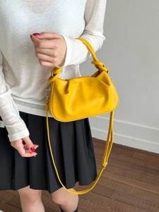 Bright yellow pleated cloud bag with knotted top handle and adjustable crossbody strap