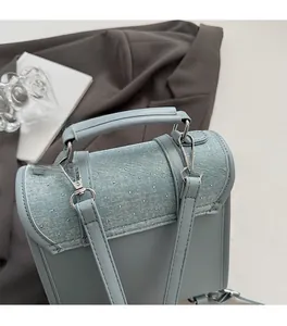 Detail of blue leather handbag featuring denim flap with silver rhinestones and hardware