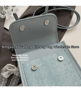 Close-up of gray-blue PU leather handbag showing dual magnetic snap button closure details