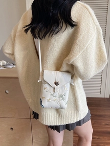 White mini crossbody phone bag with floral embroidery and gold heart metal clasp