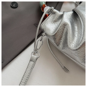 Detail of silver metallic wrinkled bucket bag with colorful translucent bead charms