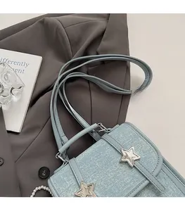 Detail of light blue denim tote with silver star buckles on a blazer background